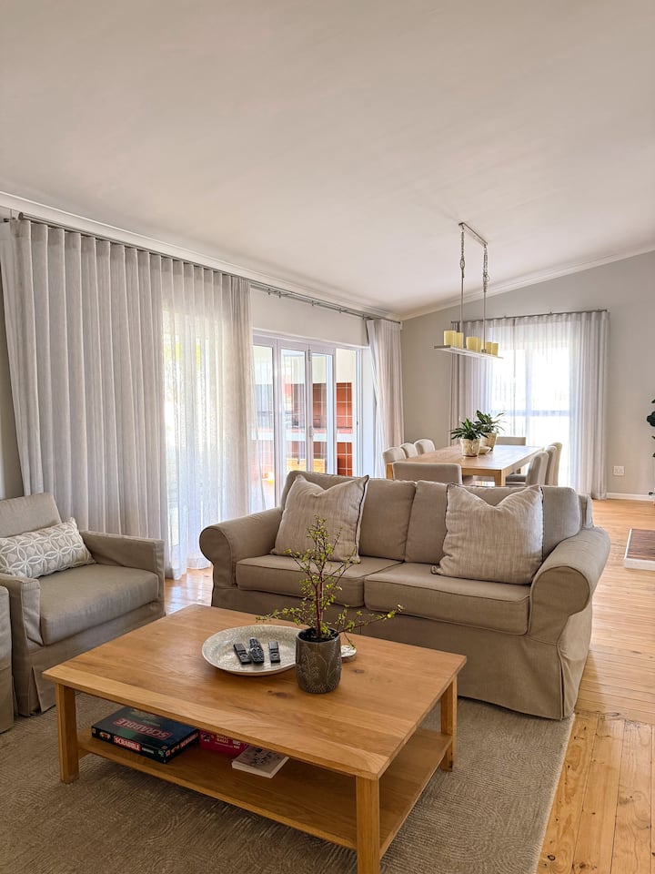 Отпуснете се в уютната всекидневна с отворена планировка, която разполага с плюшени мебели, смарт телевизор и камина на дърва за уютни вечери. Големите плъзгащи се врати се отварят към терасата, създавайки лесен поток между вътрешното и външното пространство, идеален за отдих или забавления.