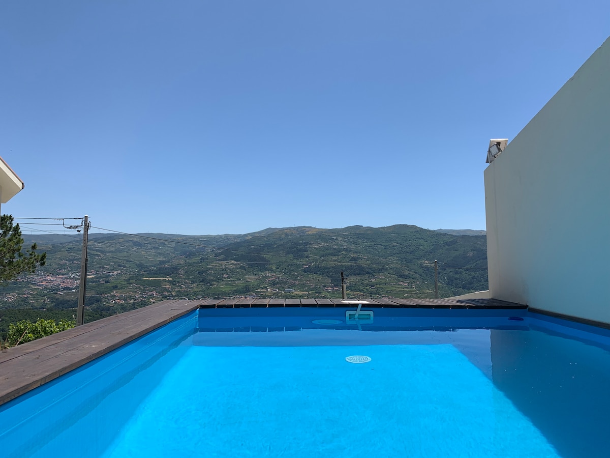 A private swimming pool is situated on a raised deck, offering expansive views of the surrounding hills and valley. The clear blue water reflects the bright sky, creating a serene setting ideal for relaxation and enjoyment of the natural surroundings.