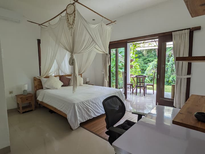 חדר שינה זוגי גדול עם דלתות כפולות לגינה ולג'ונגל. בחדר יש מזגן, שולחן עבודה, כיסא משרדי, חדר רחצה צמוד ושפע של מקום אחסון 