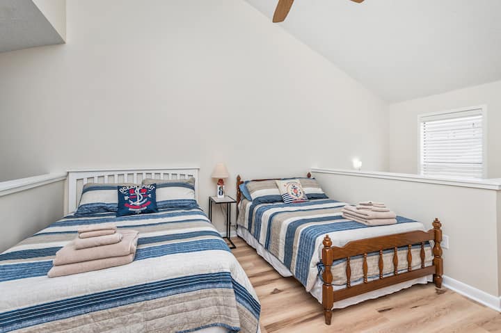 The loft bedroom offers queen and full size beds, tv with cable, ceiling fan, dresser, luggage rack, and bedside table with outlets & a USB port.