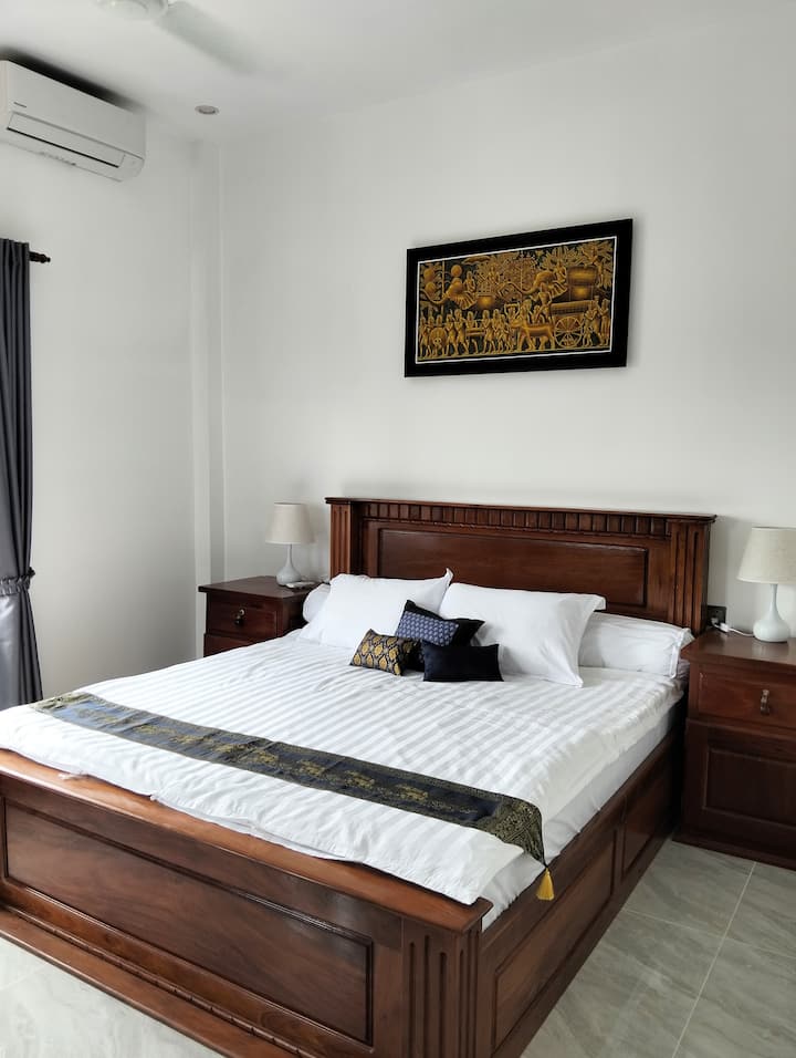 Master bedroom with AC, ceiling fan, comfortable workspace, and two windows with countryside views. Iron and ironing board available.
