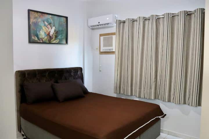 Quarto espaçoso e confortável, com cama de casal, cama de solteiro, colchão extra, guarda-roupa, televisão e ar-condicionado, proporcionando noites tranquilas de descanso.
