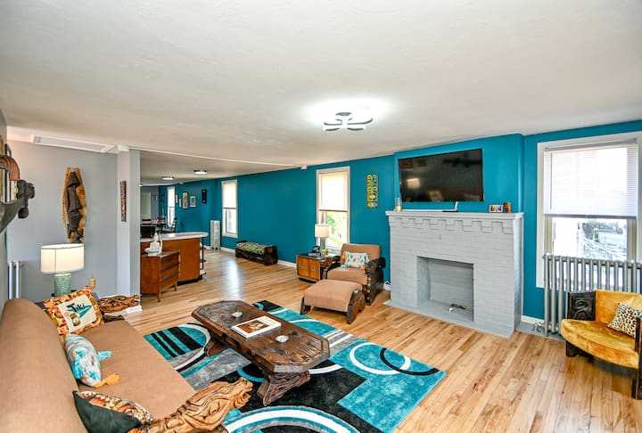 Поглед кон дневната соба од кујната, со ретро мебел и уметност на Witco, Kymm! Уметност од чакал и обновени оригинални дрвени подови. 