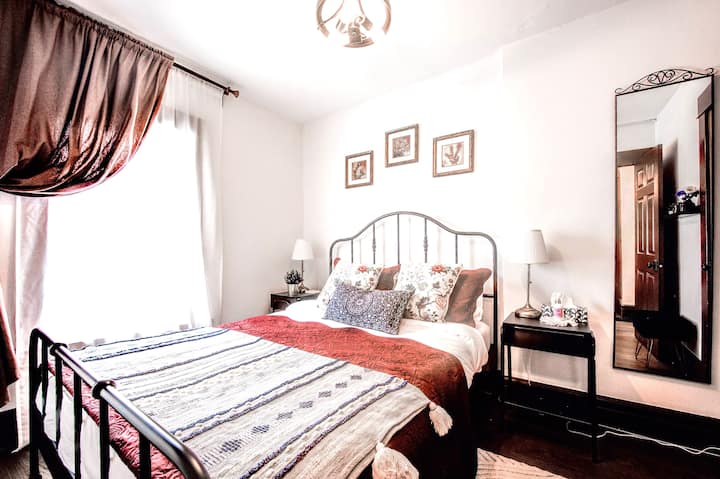 חדר שינה ראשי מזמין עם מיטת קווין סייז, מצעים נקיים ואור טבעי מרגיע — מושלם למשפחות.