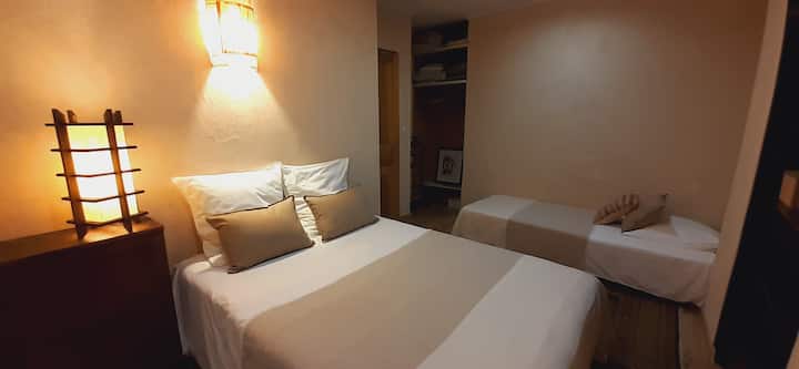 Chumba cha kulala kilicho na kitanda cha watu wawili na kitanda kimoja, rafu, kabati la nguo.