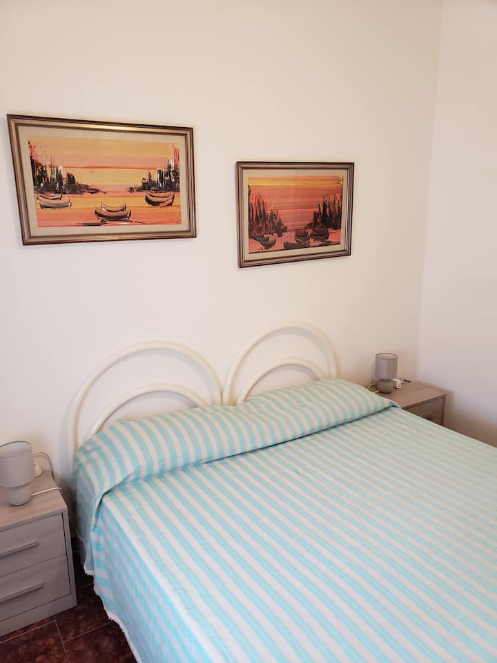 This double bedroom, downstairs, has a queen size bed, night tables with drawers, lamps and charging stations, a full armoire . The DSL line enters the house in this room and the modem is above the armoire. There is a bathroom next door.