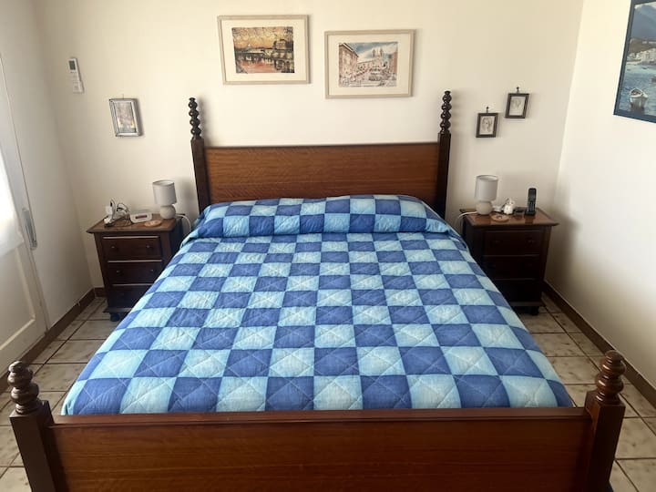 Primary bedroom, upstairs. Furnishings include a queen size bed with nightstands, a wardrobe and a chest of drawers, all handmade by local artisans out of solid wood. This room opens to a large terrace with sea views. The blue bathroom is next door.
