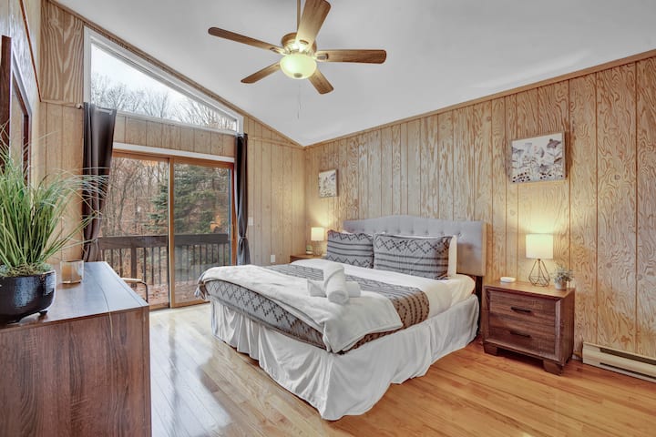 A peaceful king bedroom wrapped in warm wood tones, with direct access to the Jack-and-Jill bathroom and forest views from the private balcony.

