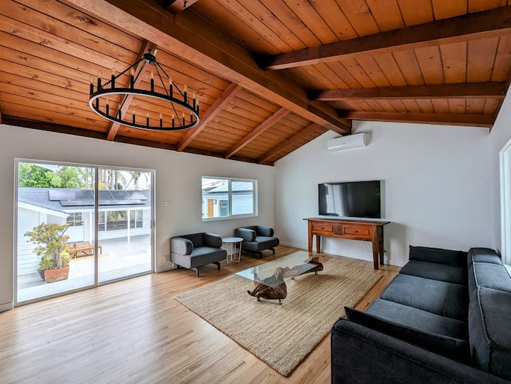 L'élégant salon dispose d'un canapé-lit confortable, de chaises longues et d'une télévision avec une vue imprenable sur la cour et les palmiers. La porte coulissante offre un accès extérieur, créant un espace accueillant et luxueux parfait pour que les voyageurs puissent se ressourcer.