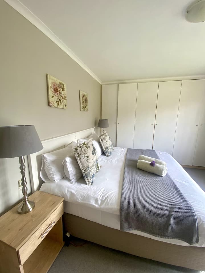 Მთავარი საძინებელი, დიდი საწოლი, სანათის სადგამები და საწოლის გვერდით მაგიდები