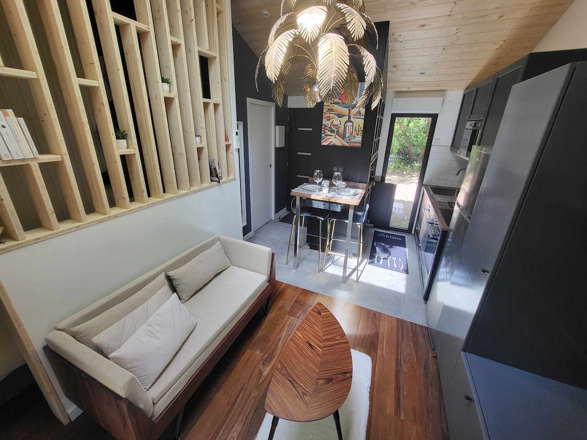 A modern interior is showcased with wooden accents and a high ceiling. A cozy sofa is positioned beside a uniquely designed coffee table. A dining area for two is set with elegant tableware, and large windows allow natural light to brighten the space.