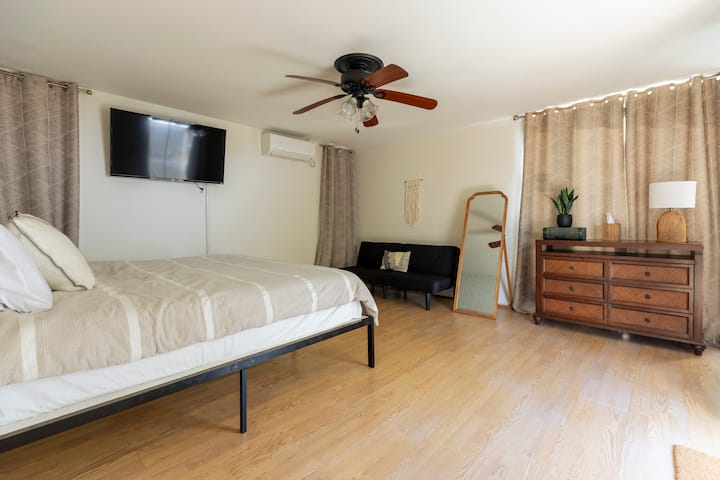 Glavna spavaća soba s bračnim krevetom, ormarom, komodom, ogledalom pune dužine, futonom, klima-uređajem, TV-om i kliznim vratima koja vode do stražnjeg dvorišta.