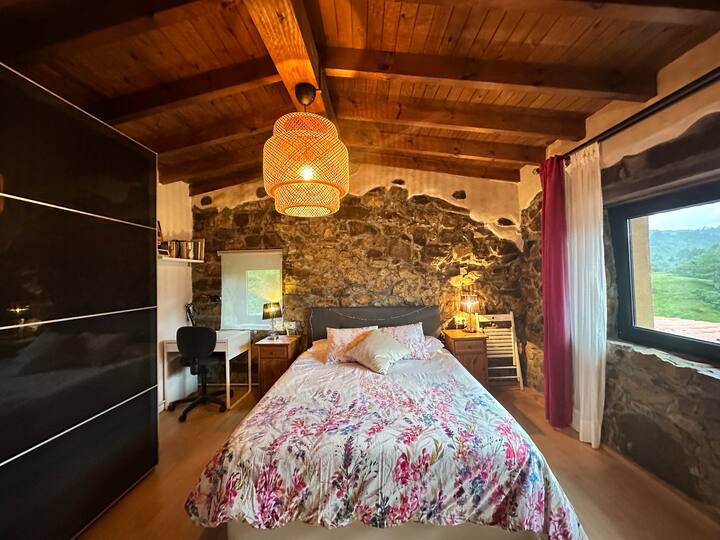 Dormitorio principal amplio y luminoso, con cama King size, paredes de piedra natural y una atmósfera que combina tradición y confort.