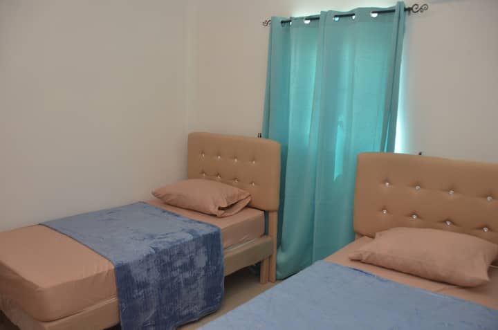Relájate en este espacioso dormitorio, con dos camas individuales y amplio espacio en el armario. Se proporciona aire acondicionado y ventilación para garantizar tu comodidad.