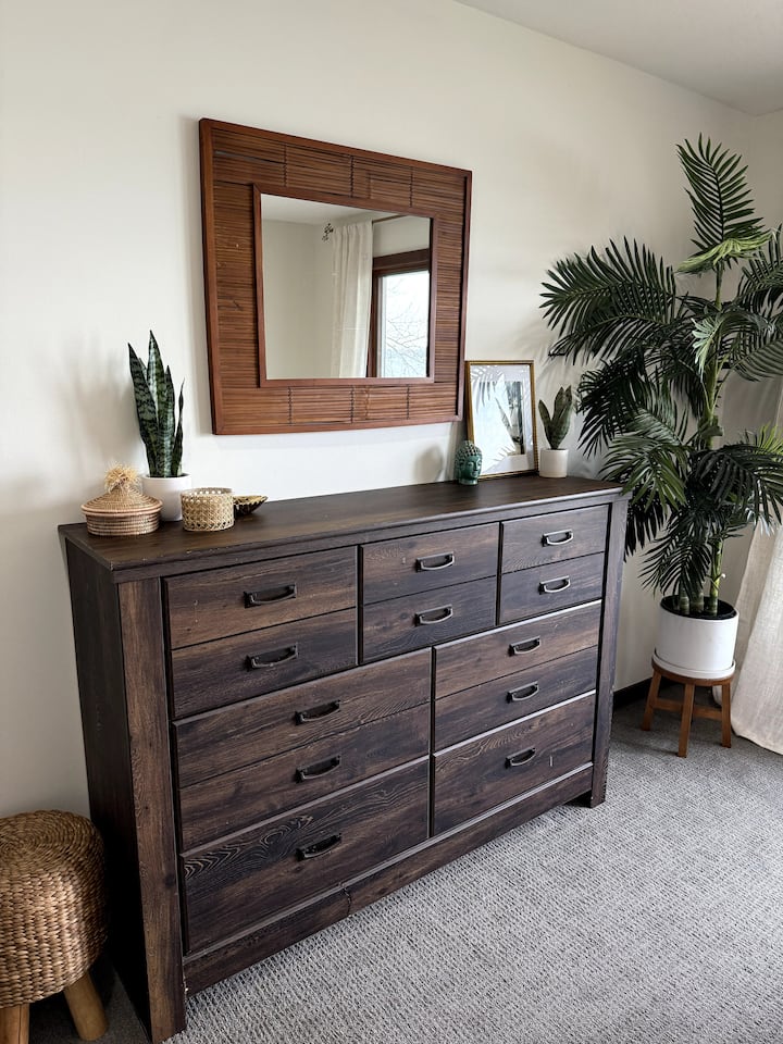 Elegante cassettiera con accenti tropicali, trame naturali e un grande specchio che porta luce e calore allo spazio.
