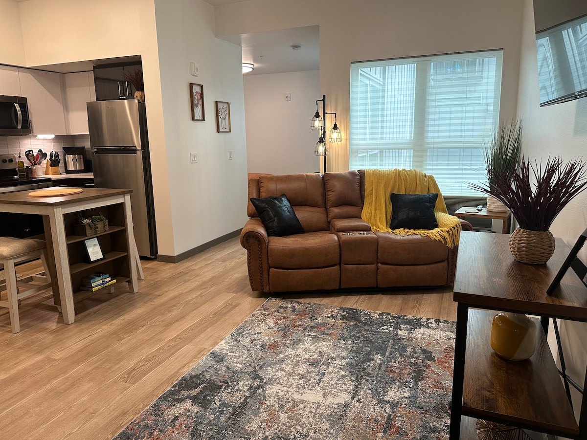 Living Room Space with brand new comfy couch that reclines on both ends and the center has a storage area and table cup holders.