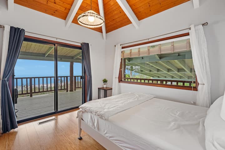 Slaapkamer aan de oceaan, met schuifdeur naar lanai. Uitzicht op de kustlijn en de oceaan.