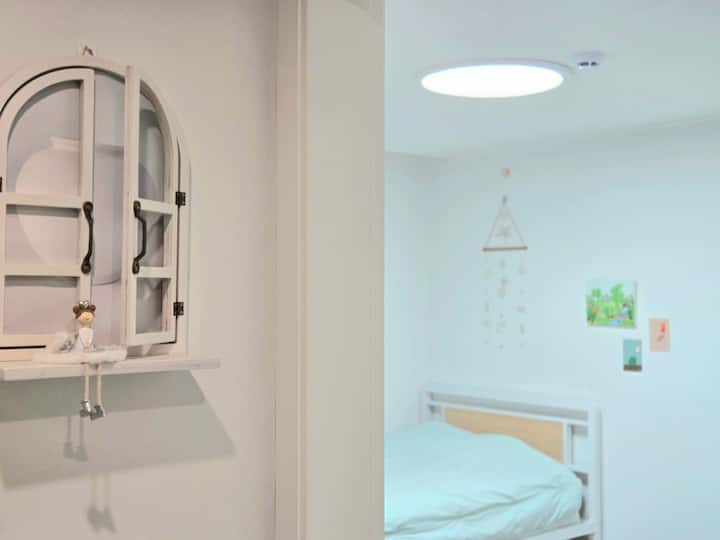 זהו חדר עם 2 מיטות יחיד מעולות ושולחן כתיבה ליד דלת הכניסה.