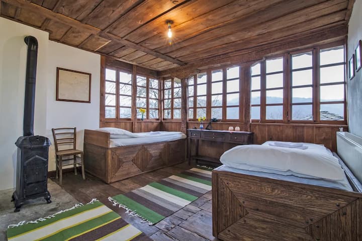 Bedroom where rustic charm meets breathtaking mountain views. This cozy wooden bedroom reflects the beauty of Central Balkan rural architecture and offers a serene environment surrounded by lush forests and majestic peaks.