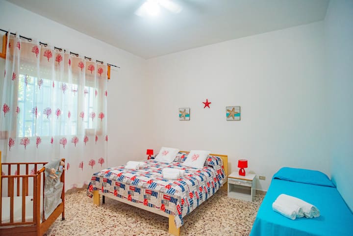 Large air-conditioned room, with a window. There is a double bed, a single bed, a crib, and two wardrobes.