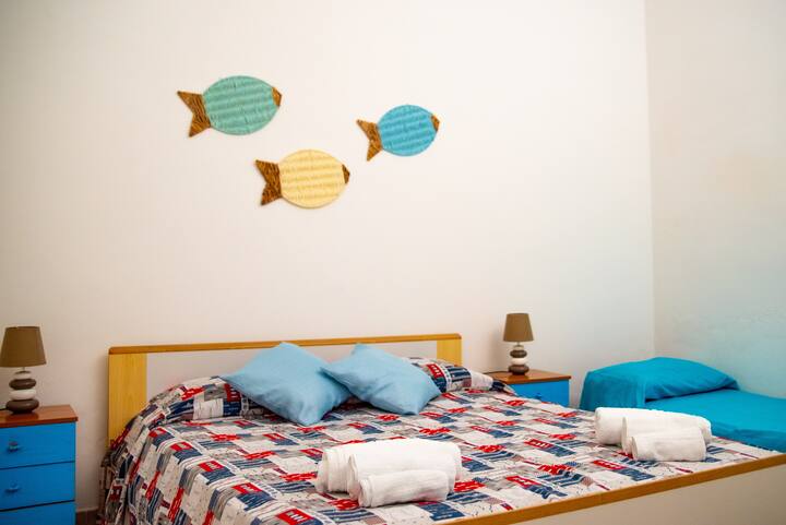 Air-conditioned room with a double bed and a single bed. There are closets and a ceiling fan.