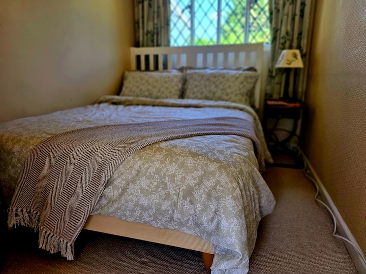 Dvojlôžková izba so šatňou, zábradlím a výhľadom do záhrady.