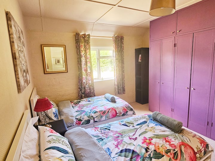 Dvojposteľová izba s množstvom úložného priestoru a výhľadom do záhrady.