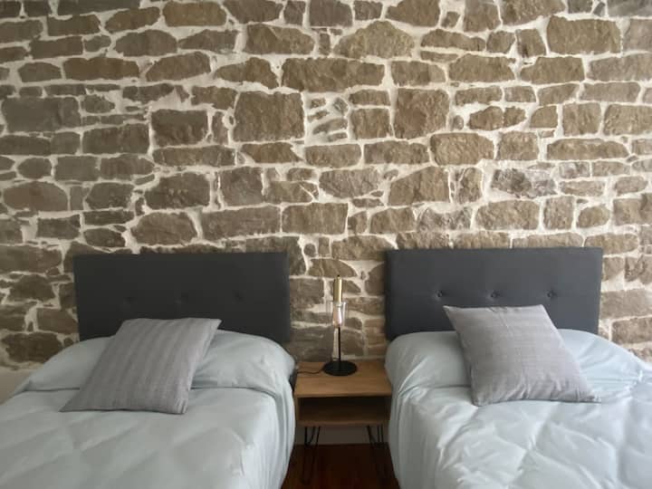 חדר שינה מרווח בגודל 16 מ"ר עם 2 105 מיטות ואזור עבודה.