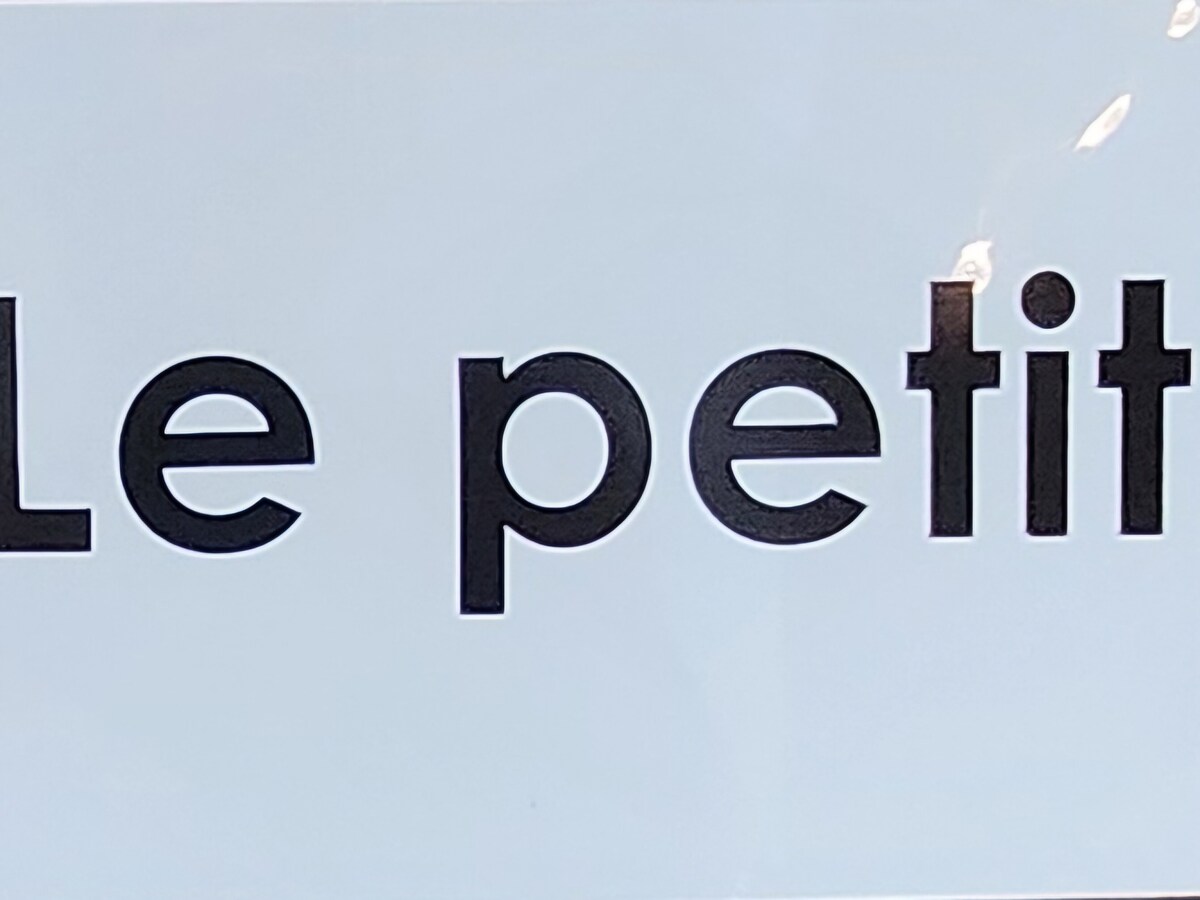 A clear sign displays the words 'Le petit' in bold, black letters against a light-colored background. The simplicity of the design draws attention to the text.