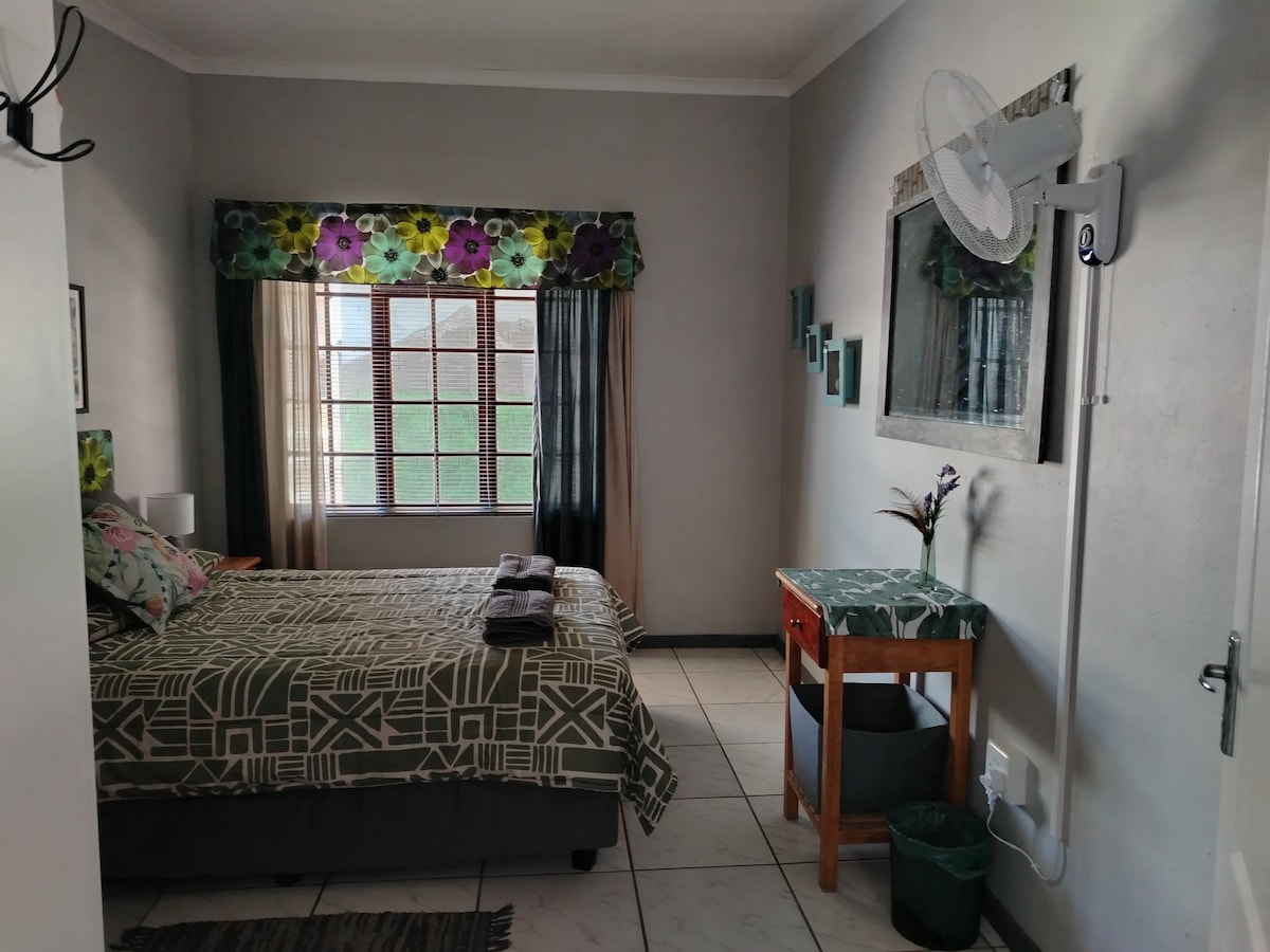 ห้องนอนหลักพร้อมเตียงคู่ตู้เสื้อผ้าขนาดใหญ่และพัดลมติดผนัง