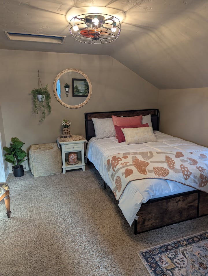 Este dormitorio cuenta con una cama tamaño queen con ropa de cama cómoda y almohadas extra. La cabecera acolchada tiene un enchufe para cargar cómodamente tus dispositivos electrónicos. 