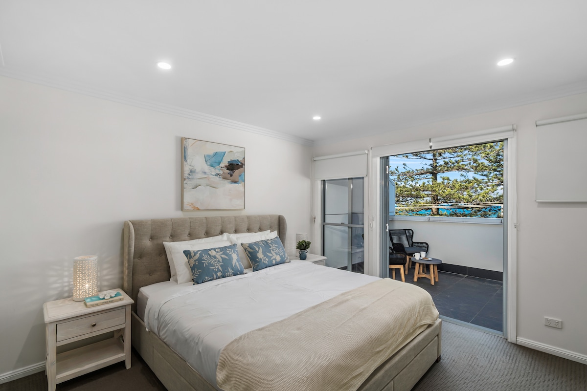 The primary bedroom offers a serene space, complete with a king-sized bed, a private balcony with cosy seating, and a sleek ensuite bathroom – the perfect space to unwind and relax.