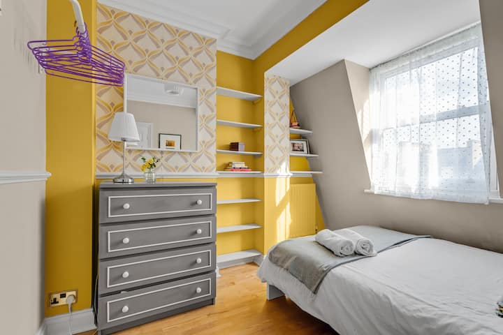 Una cama doble con una barandilla para colgar ropa y una cómoda.