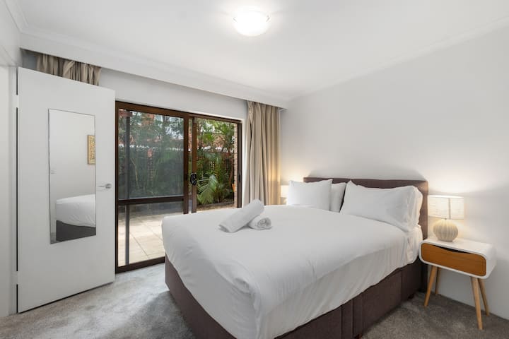 Manželská posteľ s prechádzkou v šatníku. Posuvné dvere sa otvárajú do obrovského záhradného dvora. Zablokujte závesy.