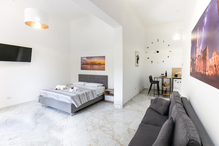 Priestranná obývacia izba s pohodlnou a pohodlnou pohovkou/posteľou a inteligentným televízorom.