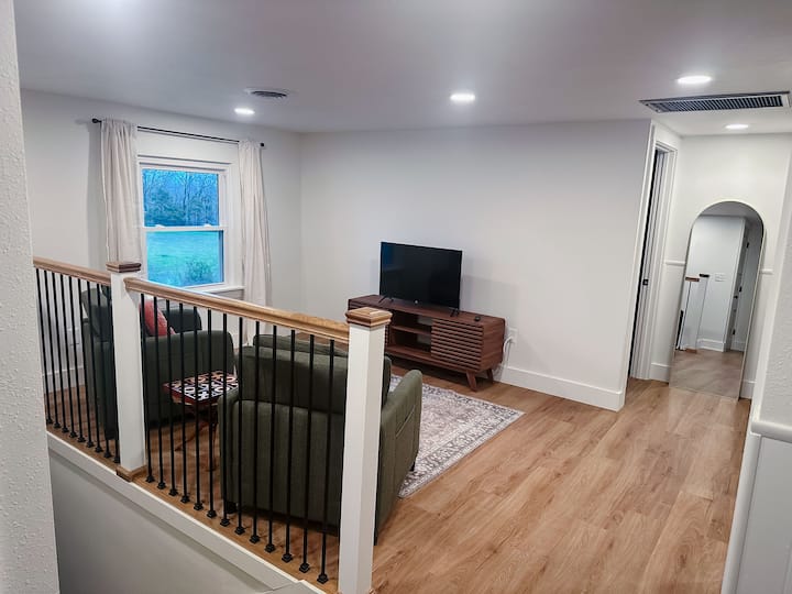 Second living room in the upstairs loft, green convertible chairs, and a smart TV.