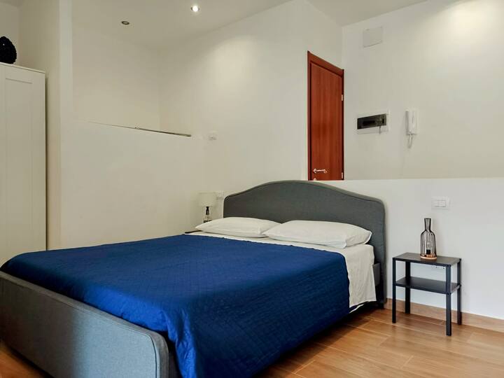 سرير بحجم متوسط مع مرتبة ميموري فوم، وطاولات جانبية للسرير مع مصابيح.