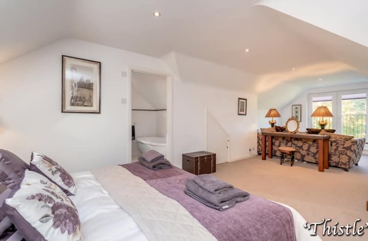 Luxurious master suite with Superking bed, ensuite bathroom and relaxing seating area with beautiful views of the grounds and loch.