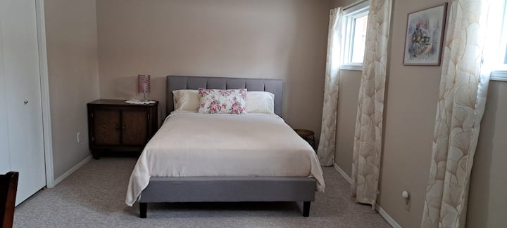amplio dormitorio con zona de escritorio.  Cama tamaño queen en marco tapizado. Colchón de felpa mediano.