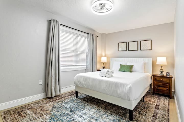 Bedroom 3: Relax in a queen-size bed, framed by three elegant pieces of artwork above the headboard. Two lamps on corner tables provide a cozy, ambient glow for winding down."