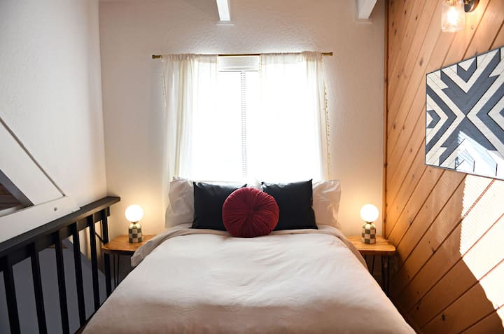 Cozy double bed overlooking the main kitchen and living area, complete with nightstands—perfect for restful nights with great views