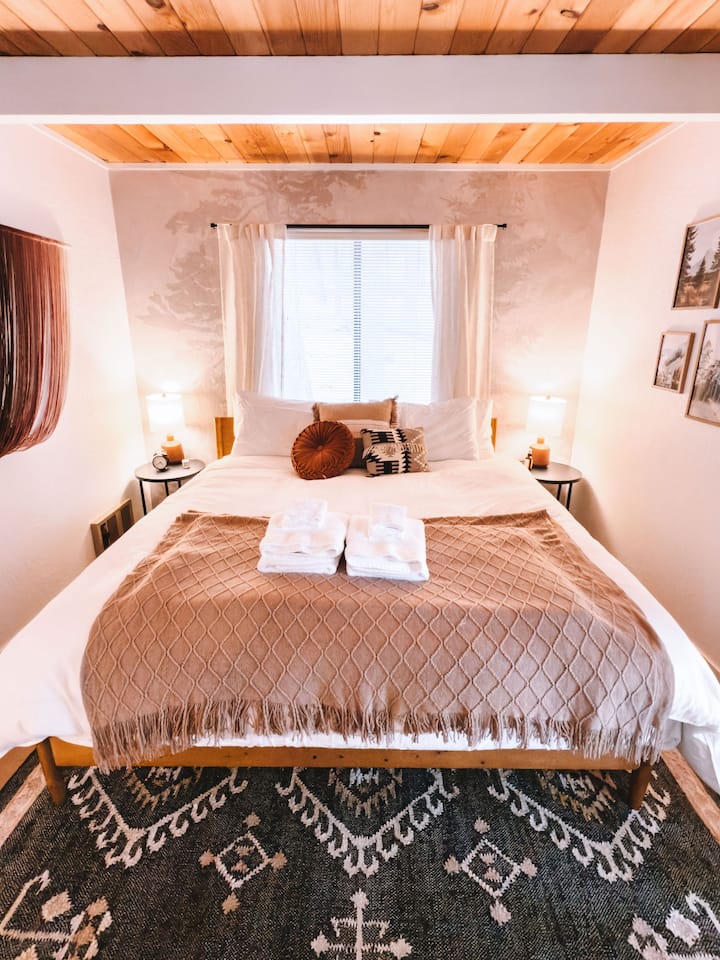 The Old Pine Room features a cozy king-sized bed, nightstands, and a large window that fills the space with natural light. Keep an eye out for deer often spotted just outside