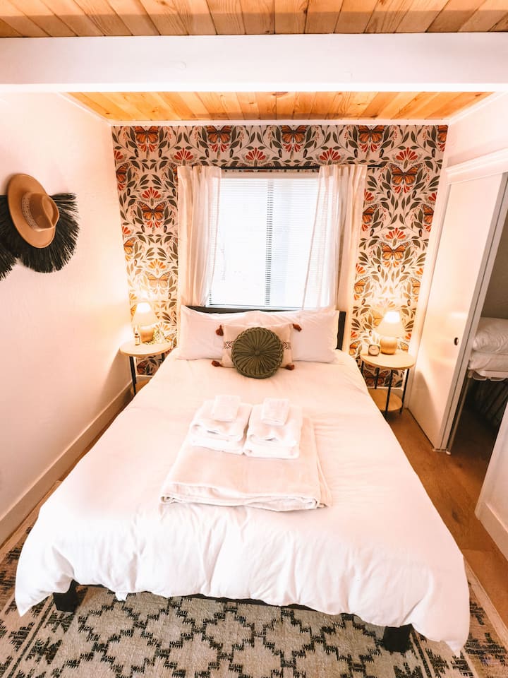 Charming butterfly-themed bedroom featuring a comfy queen-sized bed and a sleek work desk—ideal for relaxing or getting some work done in style