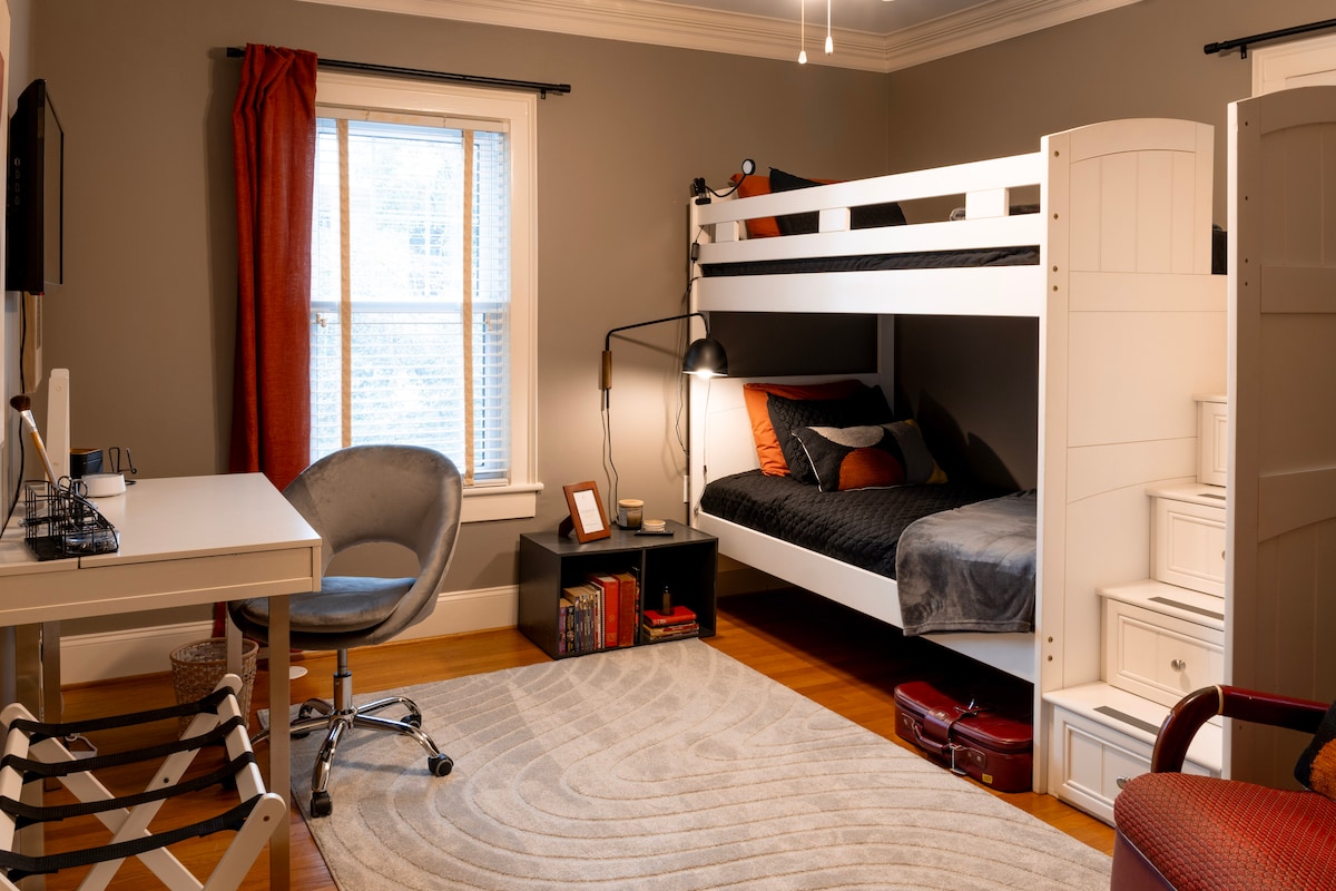 灰色卧室设有双层床、艺术家的桌子（带用品！）、智能电视、大衣柜和储物抽屉。