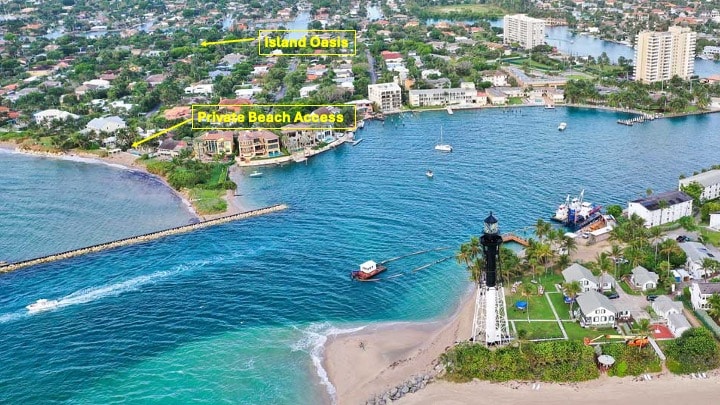 An aerial view of Island Oasis is presented, located near the Atlantic Ocean. The private beach access is visible, along with the surrounding upscale neighborhood. The historic Hillsboro Lighthouse and coastline are captured in the distance, showcasing tranquil waters and sandy beaches.