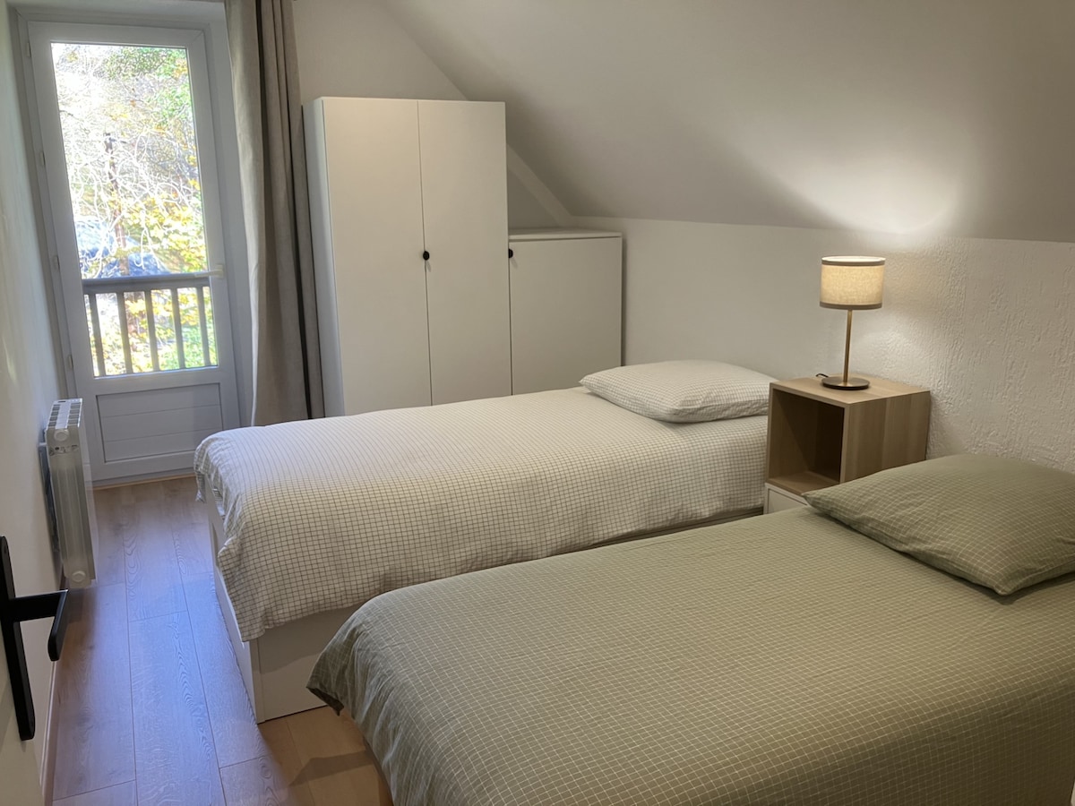 Chambre 3 : Une chambre lumineuse avec deux lits simples, parfaite pour les enfants ou amis. La porte-fenêtre apporte de la clarté et offre une vue agréable sur l’extérieur.