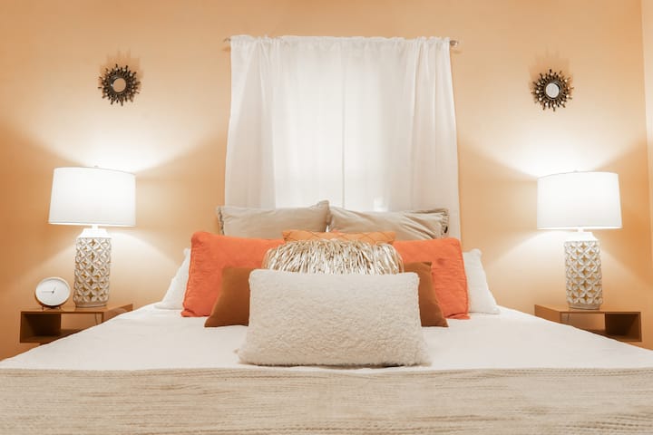 Cozy & Stylish King Bedroom: This vibrant bedroom offers a comfortable king bed, warm ambient lighting, and vintage mid-century decor, complete with a smart TV for entertainment during your stay in Bedford.