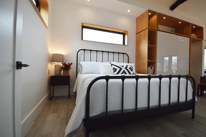 Kitanda cha ukubwa wa kifalme kilicho na kitambaa cha juu cha mto na mashuka ya mianzi. Bandari za kuchaji za usb ziko karibu na kila meza kwa ajili ya ufikiaji rahisi.