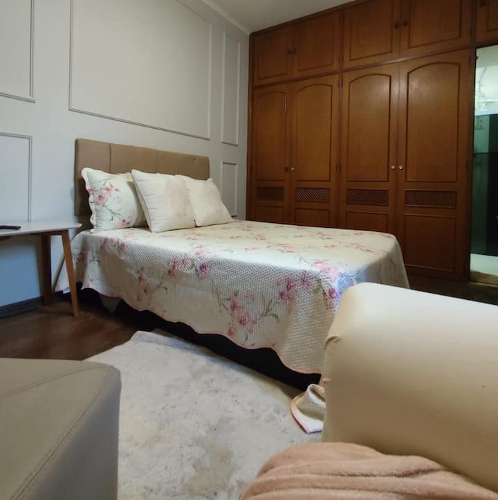 جناح بسرير مزدوج وبياضات زهرية رقيقة وديكور كلاسيكي. خزانة خشبية مدمجة وكرسي بذراعين يضمنان الراحة. مثالية لأولئك الذين يبحثون عن بيئة هادئة ومرحبة، مع سحر خالد واستخدام ممتاز للمسكن.
