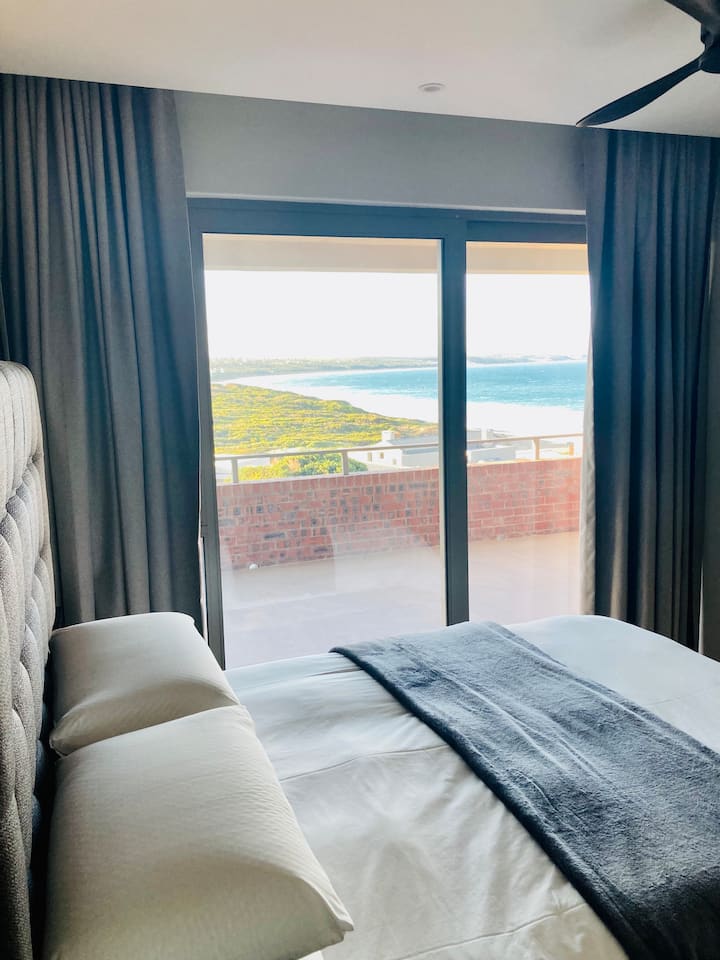 A modern, comfortable bedroom with quality linen and mattress - with a view of the ocen and direct access to the patio area